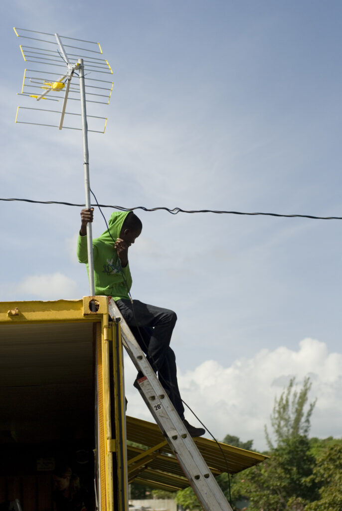 Person sitting on house adjusting antenna