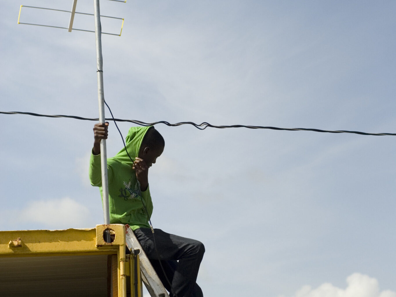 Person sitting on house adjusting antenna